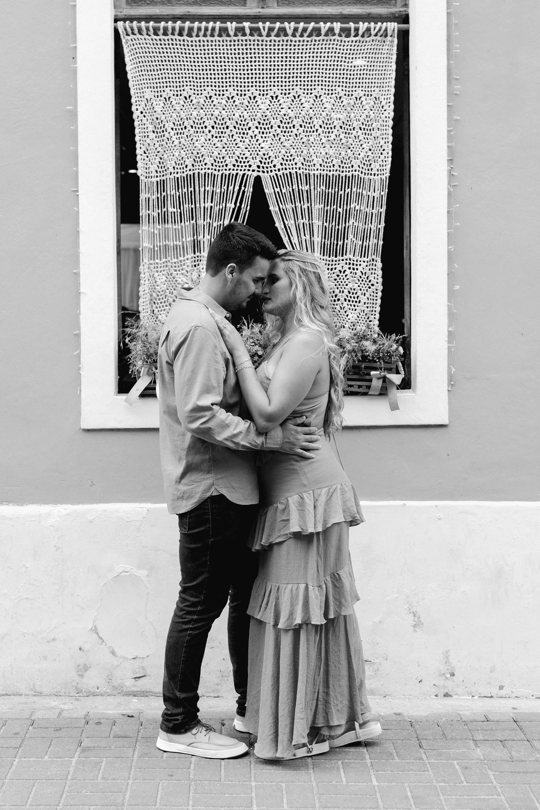 Nadia en Pieter voor 'n ou venster met 'n gehekelde gordyn